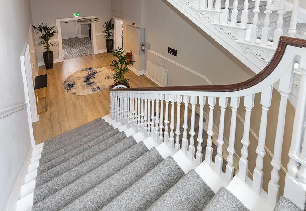 The restored Georgian staircase with white balustrades and grey carpet