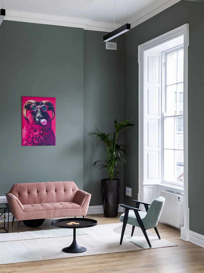 A private office lounge with a pink sofa, sage green walls and a tall Georgian window
