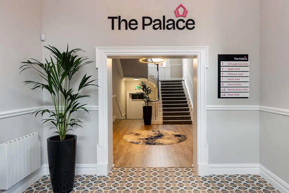 The entrance hall with The Palace logo above the door and the staircase beyond
